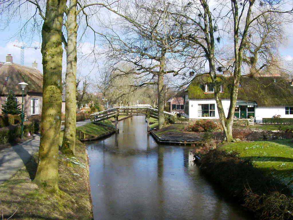 De smalle waterwegen van Giethoorn met rietgedekte boerenhuizen aan weerszijden en kleine houten botjes in het water