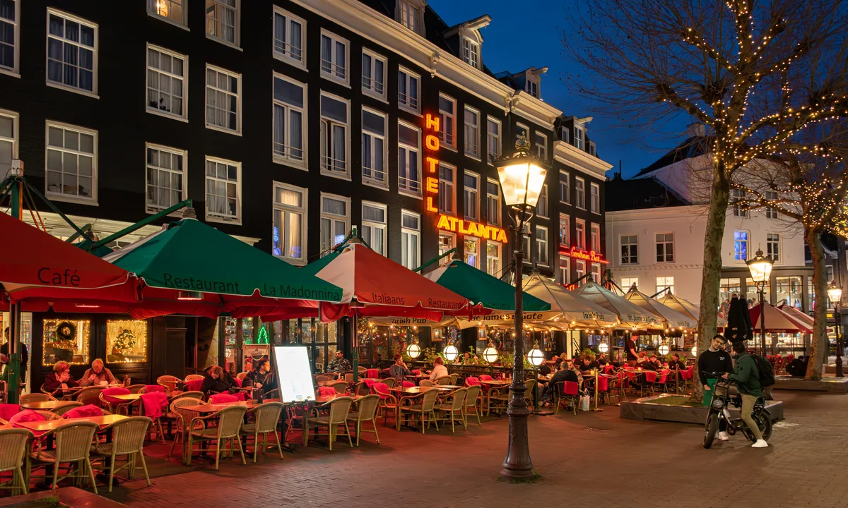 Het Rembrandtplein in Amsterdam bij avond, met de Rembrandt-standaard op het verlichte plein omgeven door terrassen